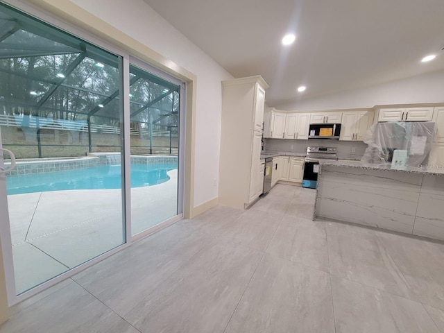 kitchen with appliances with stainless steel finishes, white cabinets, light stone countertops, and recessed lighting