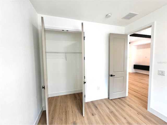 unfurnished bedroom featuring baseboards, a closet, light wood-style flooring, and visible vents