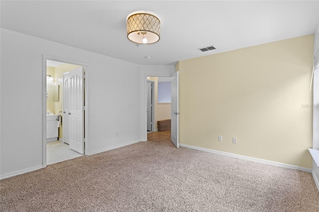 unfurnished bedroom with connected bathroom, visible vents, baseboards, and carpet floors