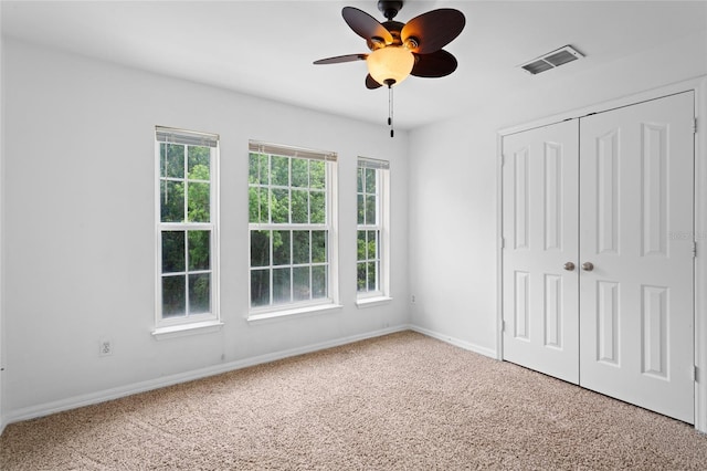 unfurnished bedroom with carpet flooring, baseboards, a closet, and visible vents