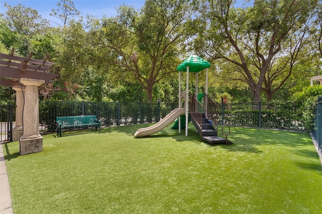 community jungle gym with a lawn, a pergola, and fence