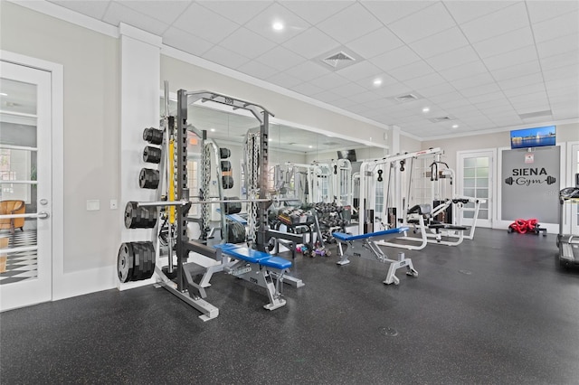 exercise room with a drop ceiling, visible vents, and ornamental molding