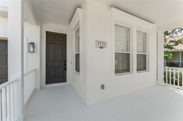 view of exterior entry featuring a porch and stucco siding