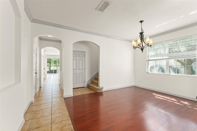 unfurnished dining area with crown molding, stairs, light wood-type flooring, a chandelier, and arched walkways