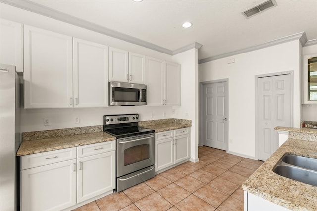 kitchen with appliances with stainless steel finishes, ornamental molding, white cabinets, light tile patterned floors, and recessed lighting