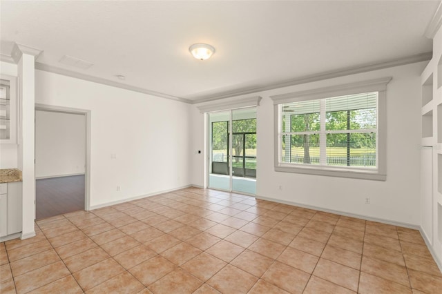 empty room with ornamental molding, healthy amount of natural light, light tile patterned floors, and baseboards