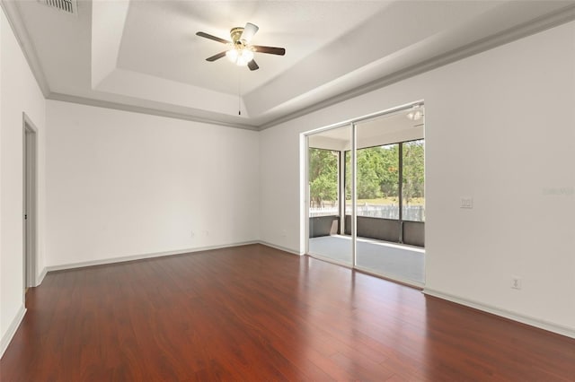 empty room featuring ceiling fan, wood finished floors, a tray ceiling, and baseboards