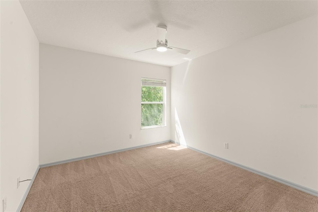 carpeted spare room with ceiling fan and baseboards