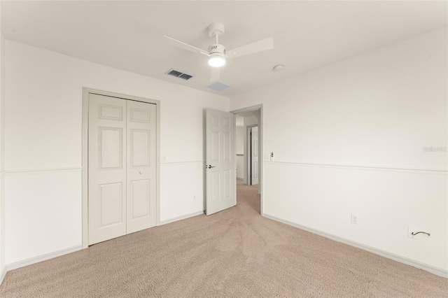 unfurnished bedroom featuring light carpet, a closet, baseboards, and a ceiling fan