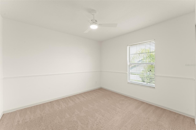 carpeted empty room featuring ceiling fan and baseboards