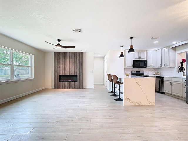 kitchen with black microwave, electric range, dishwasher, a ceiling fan, and a large fireplace
