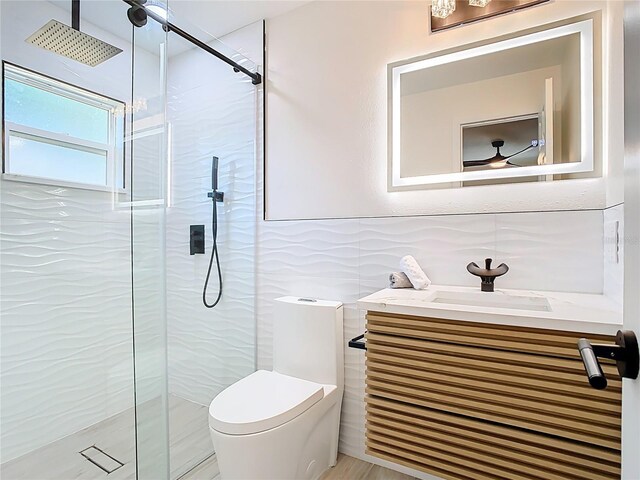 bathroom with a shower stall, toilet, vanity, and tile walls