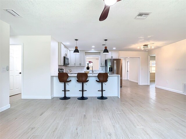 kitchen with black microwave, baseboards, ceiling fan, a peninsula, and light countertops
