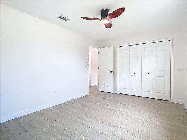 unfurnished bedroom with light wood-style flooring, baseboards, a closet, and a ceiling fan