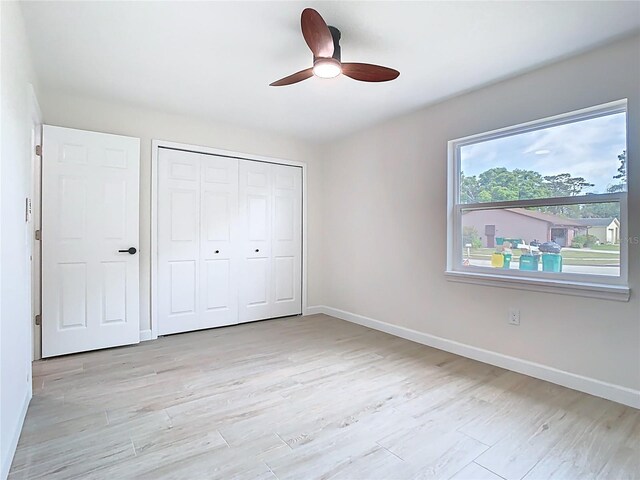 unfurnished bedroom with baseboards, a closet, light wood-style flooring, and ceiling fan