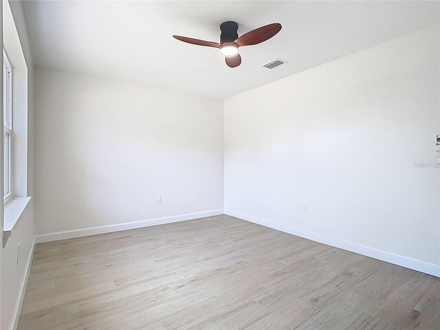 spare room featuring a ceiling fan, light wood-style floors, and baseboards