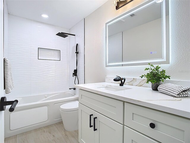 full bathroom featuring toilet, shower / bathtub combination, vanity, wood finished floors, and a textured wall