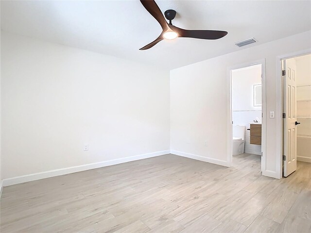 unfurnished bedroom featuring a walk in closet, light wood-style floors, baseboards, a closet, and ensuite bathroom
