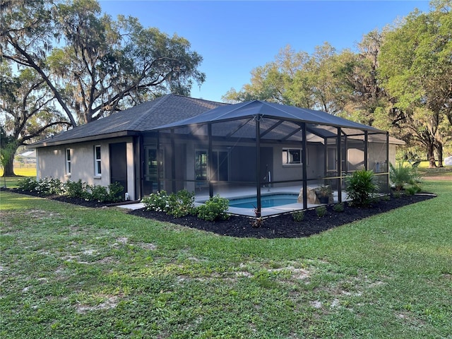 rear view of house with an outdoor pool, a yard, a patio, a shingled roof, and stucco siding