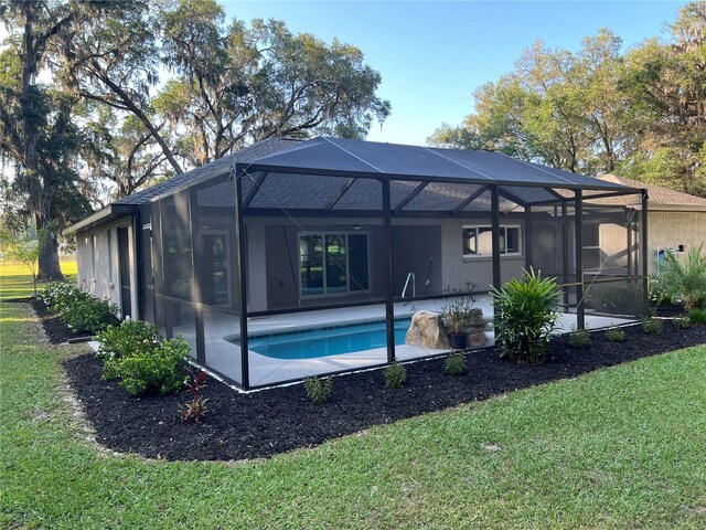 rear view of property with a patio, an outdoor pool, a lanai, and a yard