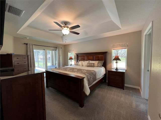 bedroom with multiple windows, a raised ceiling, carpet floors, access to exterior, and visible vents