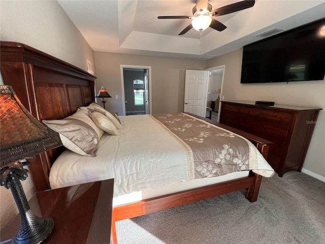 carpeted bedroom featuring a ceiling fan, visible vents, and a raised ceiling