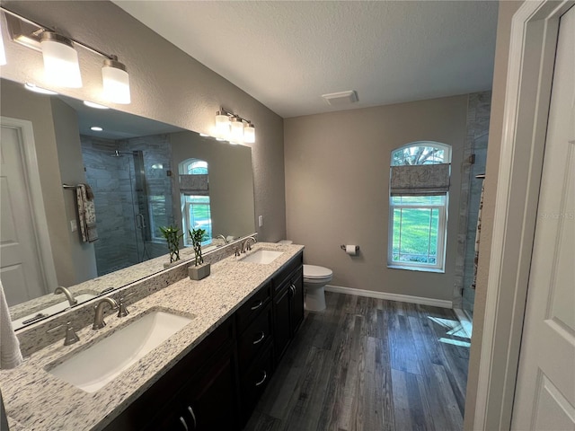 bathroom featuring a sink, a shower stall, toilet, and wood finished floors