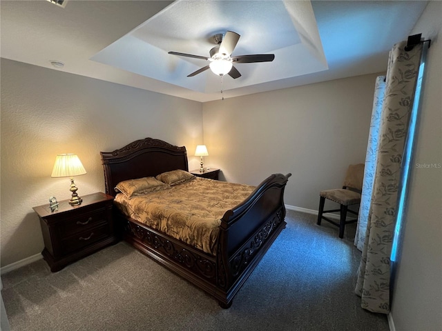 carpeted bedroom featuring baseboards, a ceiling fan, and a tray ceiling