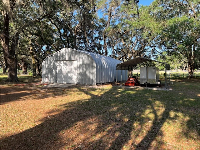 view of yard featuring a garage, a detached carport, and an outbuilding