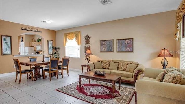 living area featuring light tile patterned floors, baseboards, arched walkways, and visible vents