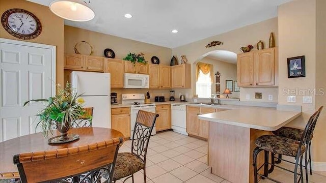 kitchen with a sink, light brown cabinets, and white appliances