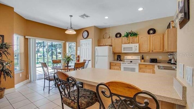 kitchen with visible vents, a sink, a peninsula, light brown cabinets, and white appliances