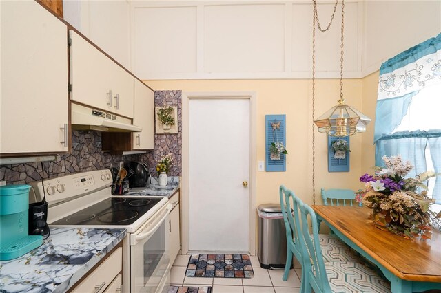 7418 Riverbank Dr, New Port Richey, FL 34655 - kitchen with under cabinet range hood, electric range, backsplash, white cabinetry, and light tile patterned floors