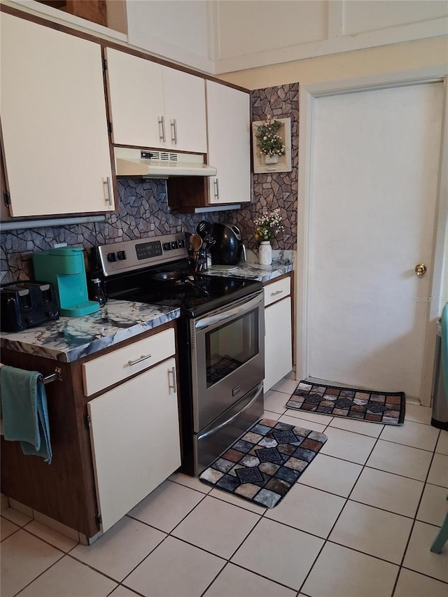 7418 Riverbank Dr, New Port Richey, FL 34655 - kitchen with stainless steel electric range oven, under cabinet range hood, tasteful backsplash, white cabinetry, and light tile patterned floors
