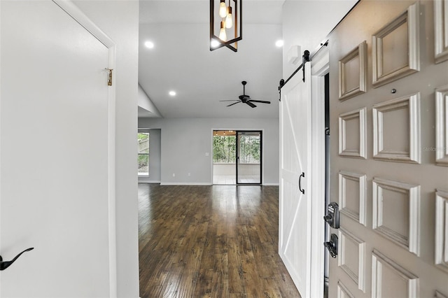 foyer entrance featuring lofted ceiling, a barn door, dark wood-style flooring, ceiling fan, and baseboards