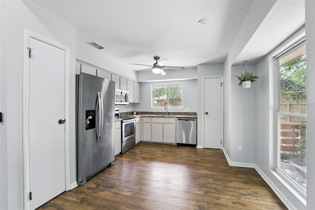 kitchen with a ceiling fan, visible vents, a sink, appliances with stainless steel finishes, and dark wood-style floors