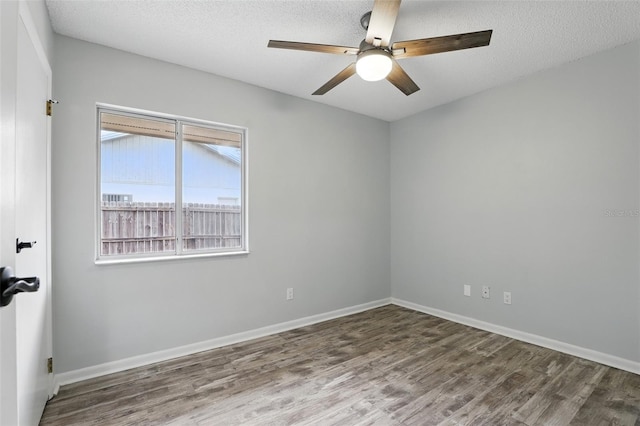 empty room with a textured ceiling, baseboards, a ceiling fan, and wood finished floors