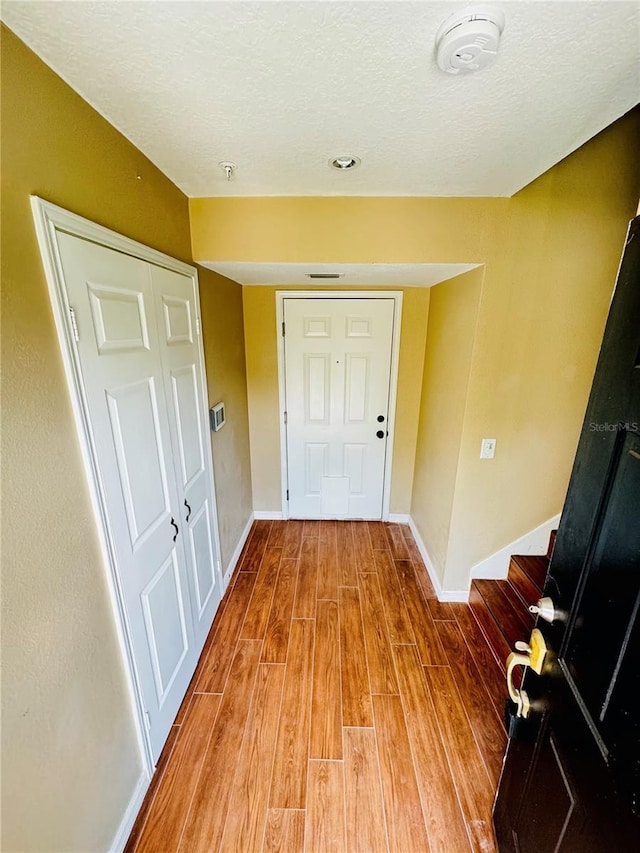 interior space featuring baseboards, a textured ceiling, and wood finished floors