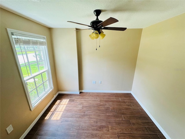 unfurnished room featuring baseboards, dark wood-style floors, and plenty of natural light