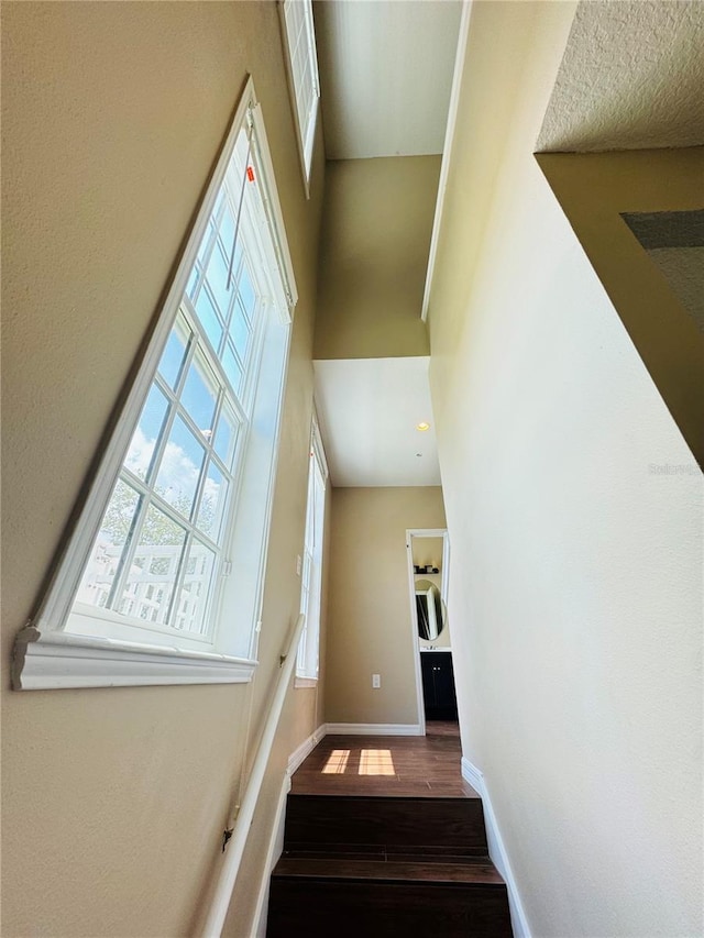 staircase with baseboards, a towering ceiling, and wood finished floors