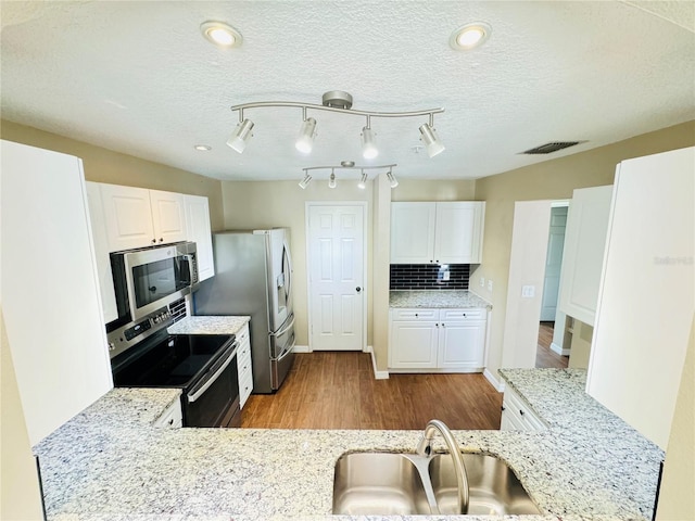 kitchen with white cabinets, stainless steel appliances, visible vents, and a sink