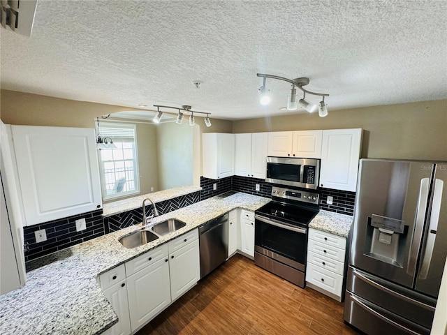 kitchen featuring light stone countertops, dark wood-style flooring, a sink, white cabinetry, and appliances with stainless steel finishes