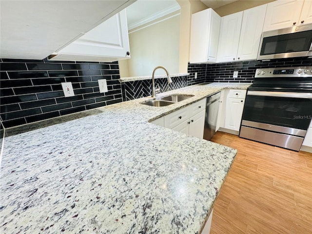 kitchen with a sink, tasteful backsplash, crown molding, white cabinetry, and appliances with stainless steel finishes