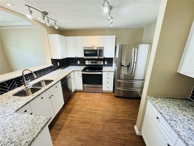 kitchen featuring a sink, stainless steel appliances, white cabinetry, and light stone countertops