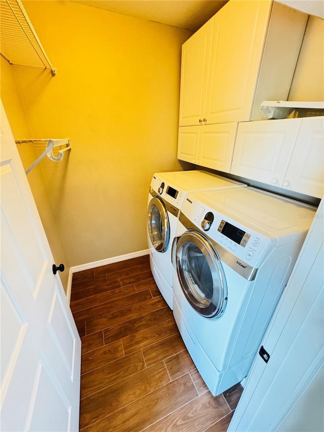 clothes washing area with cabinet space, washing machine and dryer, baseboards, and wood tiled floor