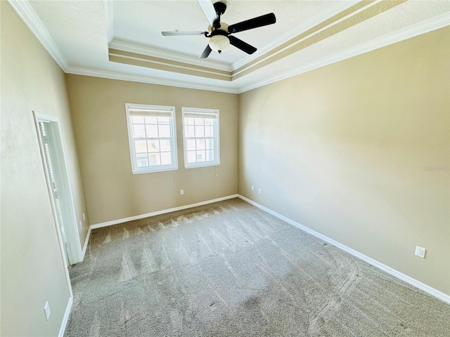 carpeted spare room with baseboards, ornamental molding, a tray ceiling, and a ceiling fan