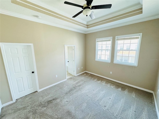 unfurnished bedroom with crown molding, ceiling fan, carpet floors, a raised ceiling, and baseboards