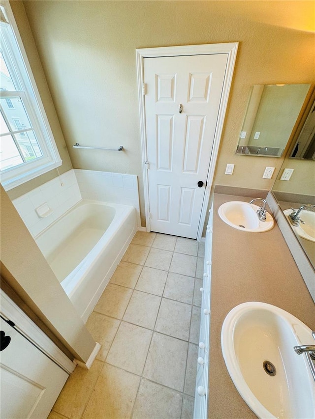 bathroom featuring a bath, tile patterned floors, double vanity, and a sink