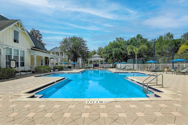 community pool with a patio area, fence, and a gazebo