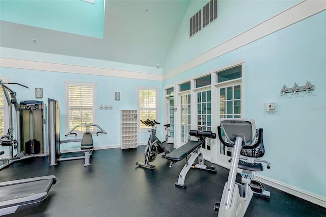 gym with french doors, baseboards, and high vaulted ceiling